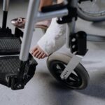 Close-up of an injured foot in a cast resting on a wheelchair, indoors.