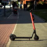 E-scooter accident lawsuit who is liable (A Voi e-scooter parked on a sunlit city sidewalk with a blurred urban background.)