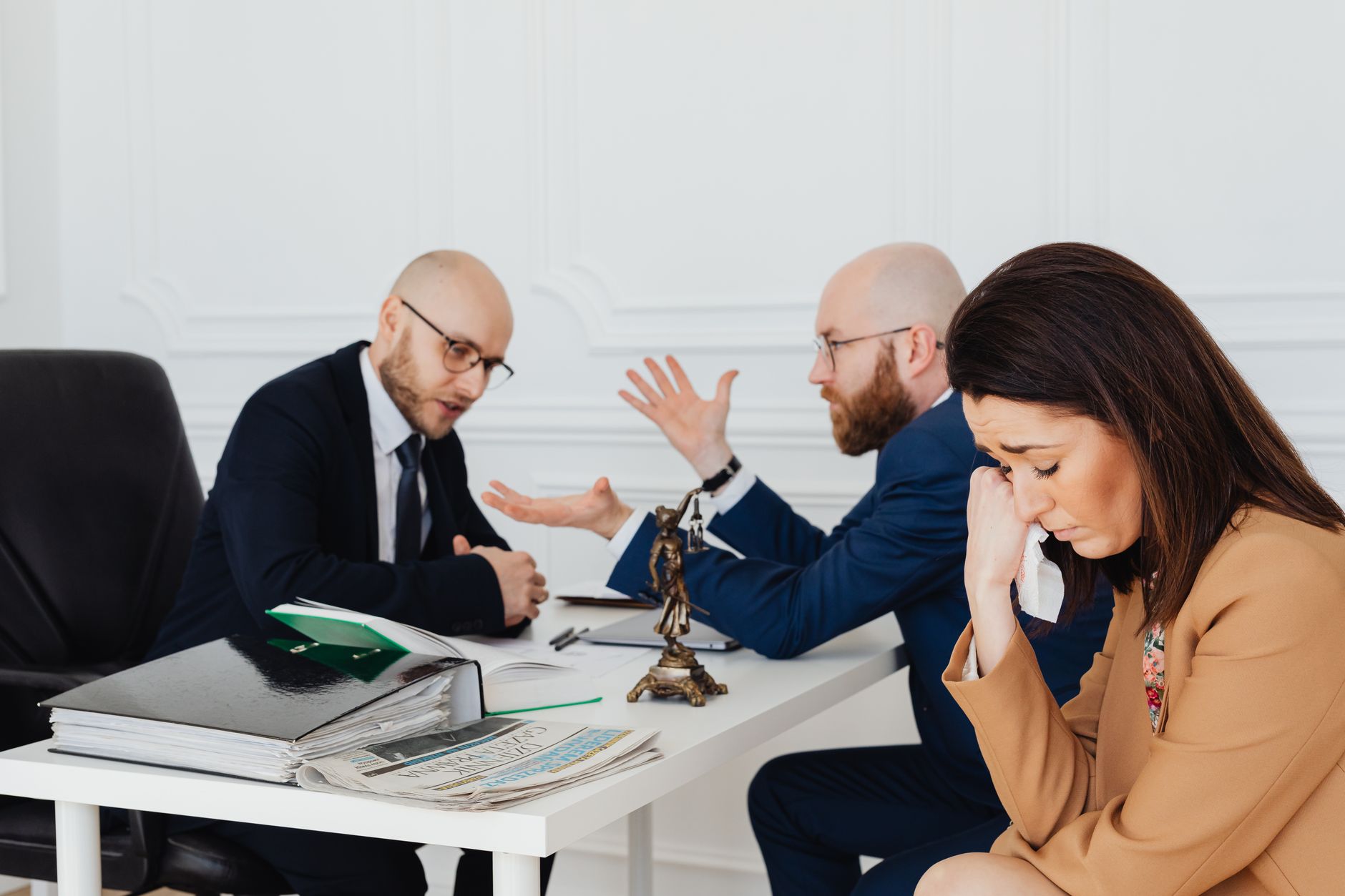 Medical malpractice lawyer (A woman appears distressed while two lawyers converse in an office.)