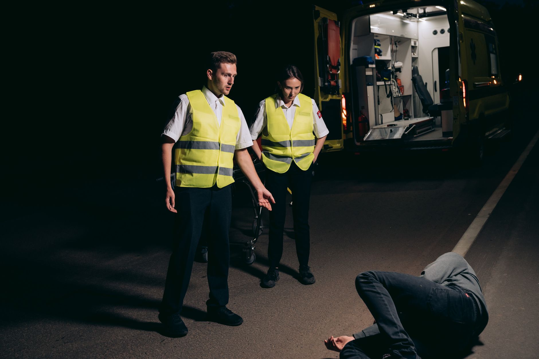 Pedestrian accident lawyer (Paramedics assist a patient on a dimly lit street, showcasing emergency response at night.)