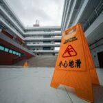 Premises liability lawyer (Yellow caution wet floor sign in a modern building courtyard with overcast sky.)