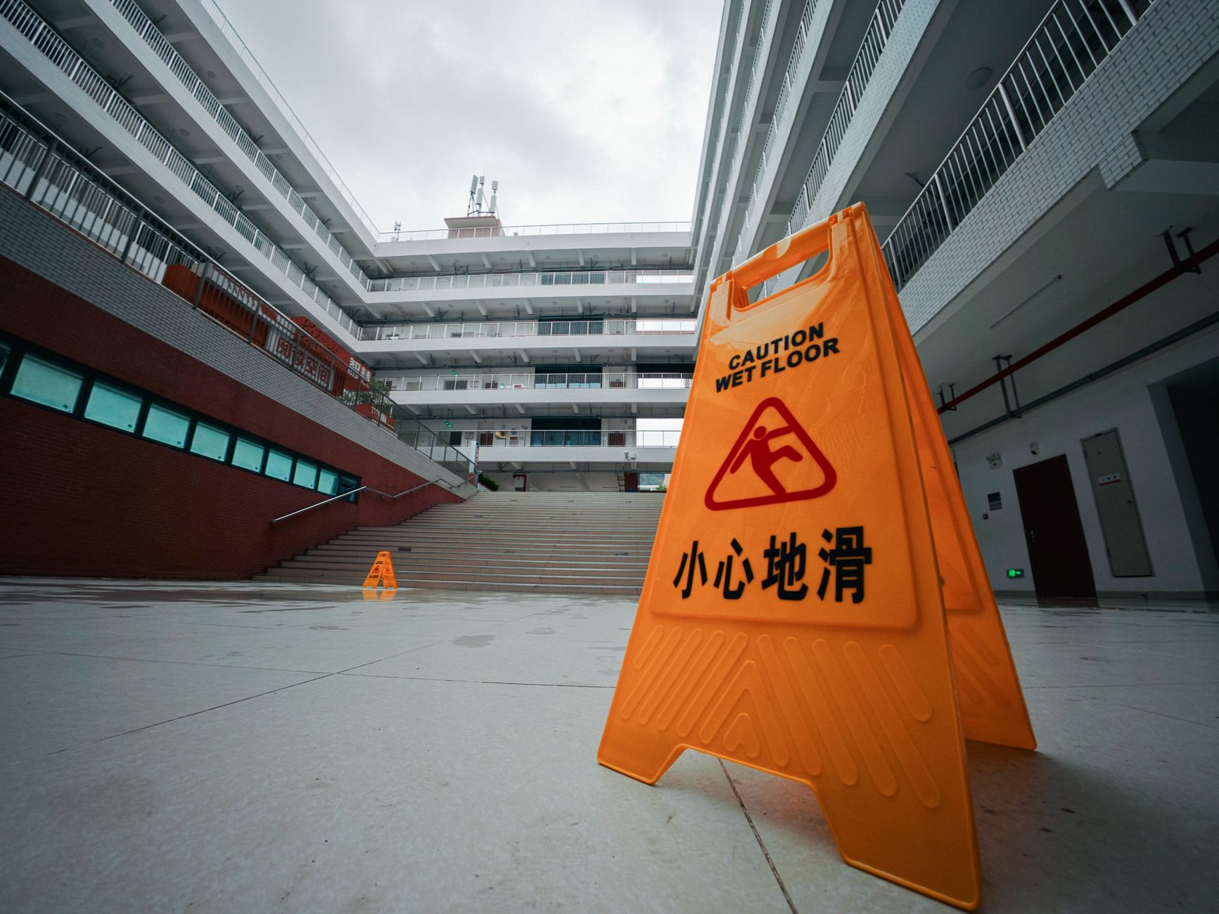 Premises liability lawyer (Yellow caution wet floor sign in a modern building courtyard with overcast sky.)