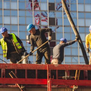 Workers comp denial appeal (A group of construction workers in safety gear actively working on a high-rise building site.)