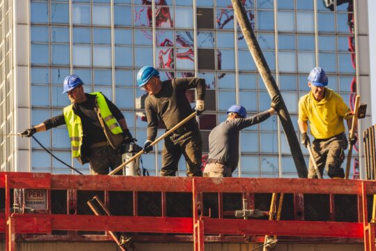 Workers comp denial appeal (A group of construction workers in safety gear actively working on a high-rise building site.)