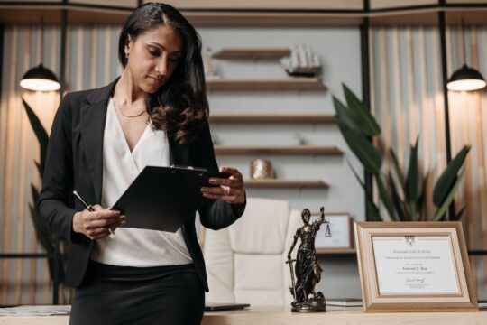 Best personal injury lawyer (Confident businesswoman reviewing paperwork in a modern law office setting.)