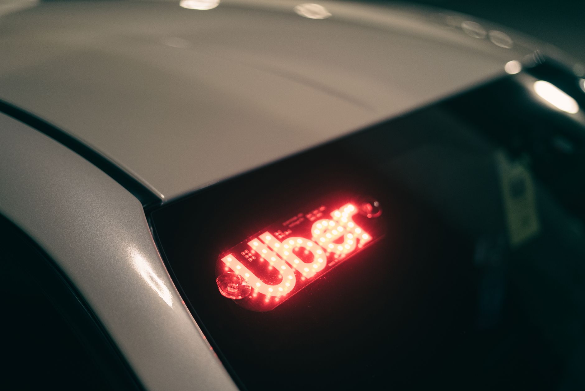 Uber accident lawyer (Close-up of a ride-sharing car with a bright red illuminated sign for night-time travel.)