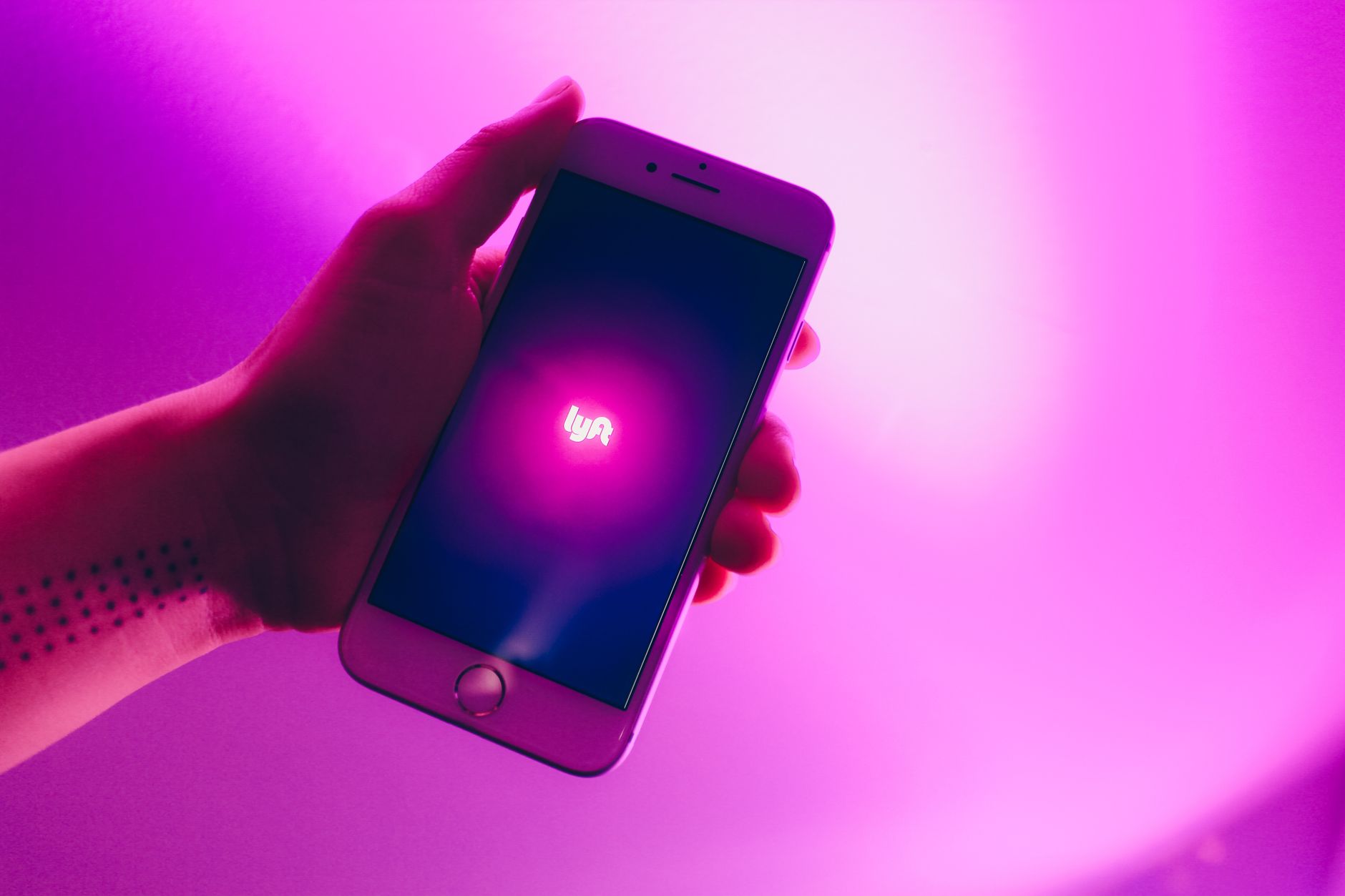 Lyft accident lawyer (A hand holding a smartphone displaying the Lyft ridesharing app with a vivid pink background.)