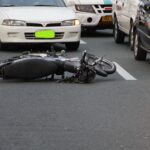 Hit and run accident lawyer (A motorcycle lies on a city road amidst traffic, indicating a recent accident.)