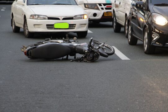Hit and run accident lawyer (A motorcycle lies on a city road amidst traffic, indicating a recent accident.)