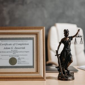 Catastrophic injury lawyer (A framed legal certificate and Lady Justice figurine on a desk in a law office setting.)