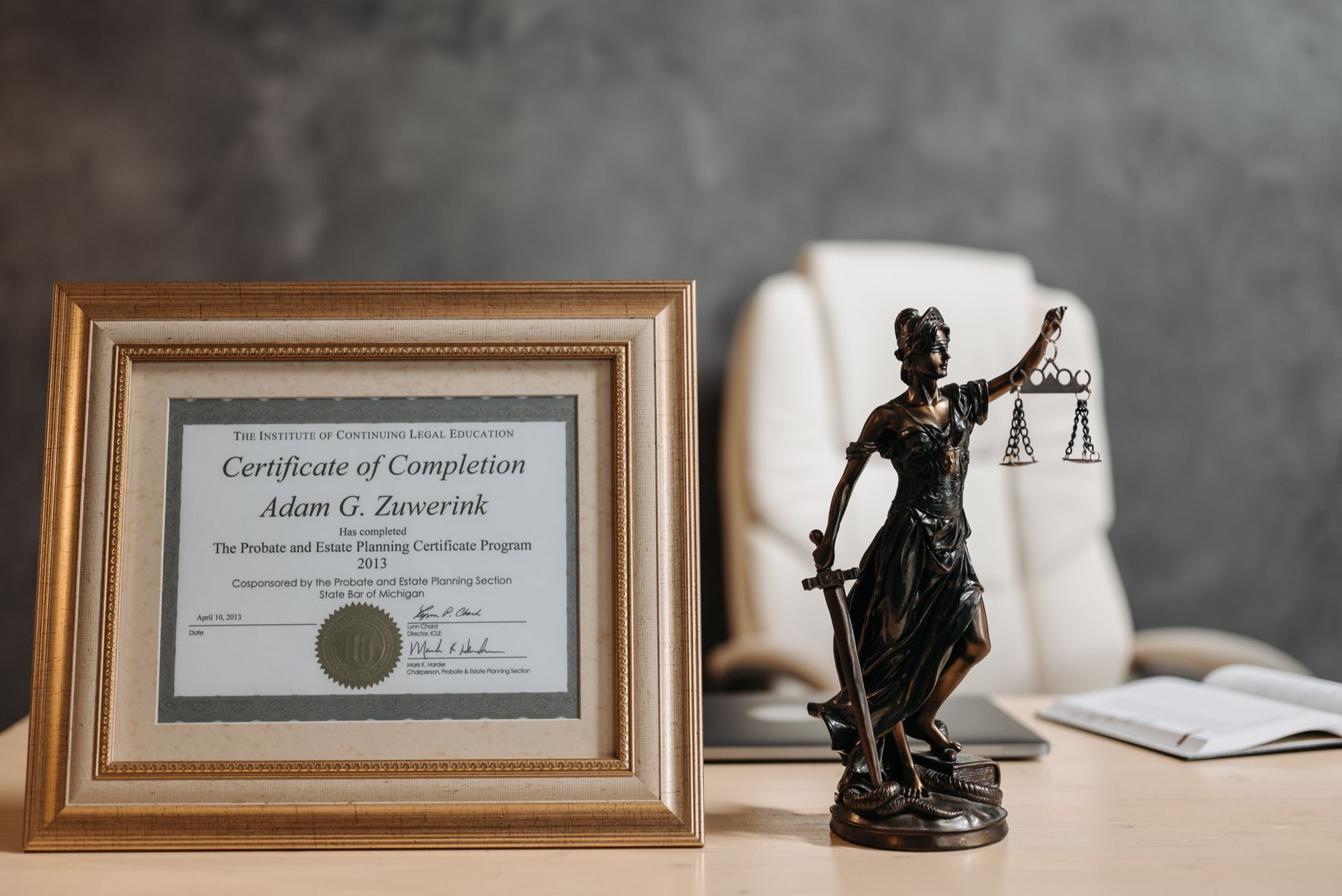 Catastrophic injury lawyer (A framed legal certificate and Lady Justice figurine on a desk in a law office setting.)