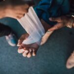 Burn injury lawyer (A detail shot showing hands applying a bandage to an injured wrist outdoors.)