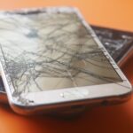Defective product injury lawyer (Two broken smartphone screens on an orange background, illustrating device fragility.)
