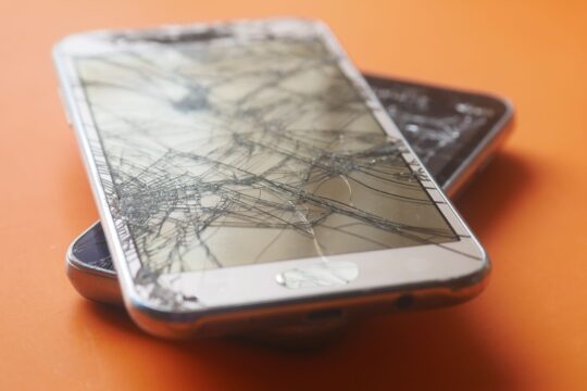 Defective product injury lawyer (Two broken smartphone screens on an orange background, illustrating device fragility.)